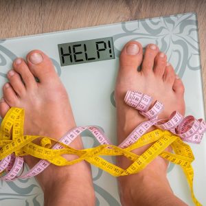 Female feet on personal scales with word HELP! - obesity and diet concept